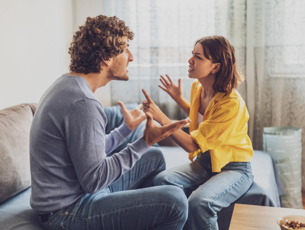 Man and woman are sitting at sofa and arguing. Relationship problems.