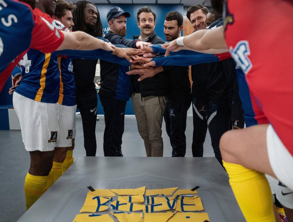 Brendan Hunt, Jason Sudeikis and Brett Goldstein in "Ted Lasso," huddled around torn "Believe" sign in season 3 finale. Some cast members have hinted at a possible season 4 of Ted Lasso