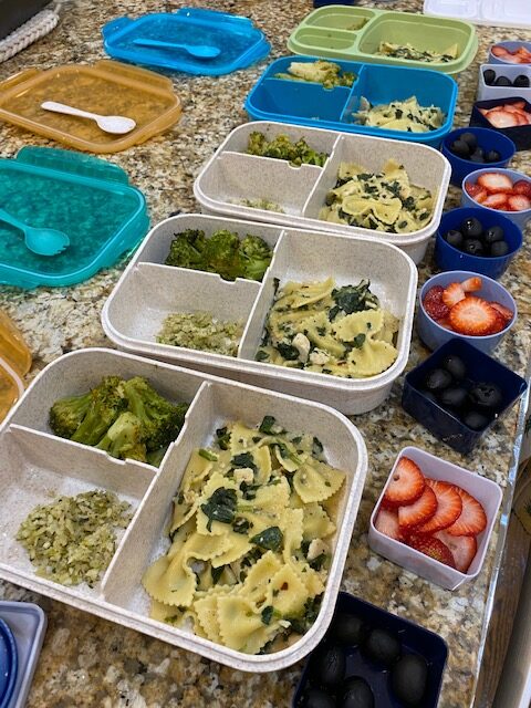 Meal prepped lunches with pasta, vegetables, and fruit. 